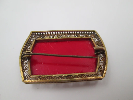 Broche para mujer. Metal dorado y resina roja. Grabados florales y cerco calado. 1960