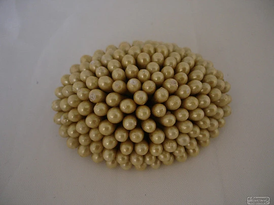 Brooch. Plated metal back. Small balls. Champagne colour. Resin