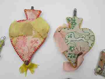 Colección de seis exvotos de tela de colores y metal. Corazones y peces. 1950