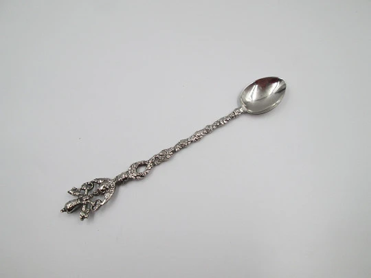 Cuchara larga ornamental. Metal plateado. Escudo pontificio, querubín y motivos florales
