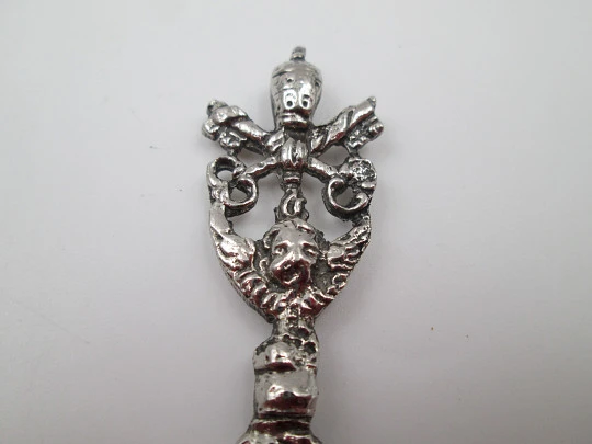 Cuchara larga ornamental. Metal plateado. Escudo pontificio, querubín y motivos florales