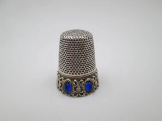 Dedal de costura. Plata de ley e interior vermeil. Cerco con piedras azules. 1950