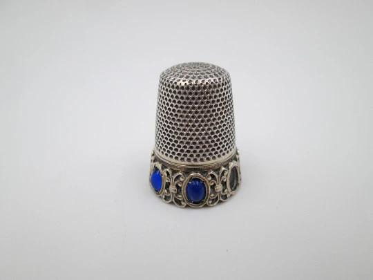 Dedal de costura. Plata de ley e interior vermeil. Cerco con piedras azules. 1950