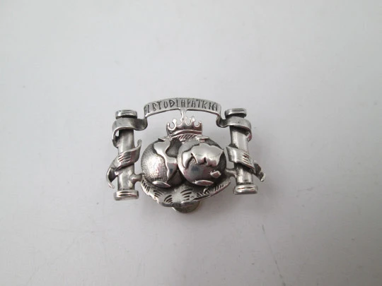 Emblema calado de solapa para caballero. Plata de ley. Motivo reales columnarios. 1980