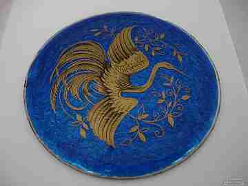 Esmalte sobre cobre. Circular. Fondo azul. Años 30. Grulla en oro