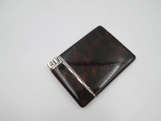 Inusual encendedor automático a gasolina con pitillera Dios. Metal plateado y esmalte carey