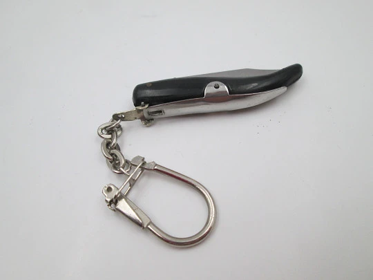 Llavero con navaja de bolsillo miniatura. Acero y resina negra. Empuñadura curva. 1980