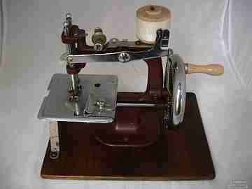 Máquina de coser miniatura. 1940. Metal granate y base de madera