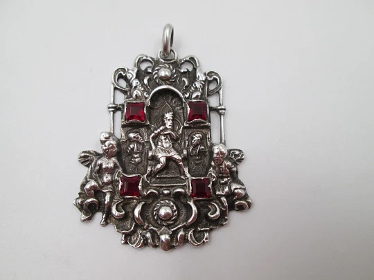 Medalla colgante pórtico. Plata de ley y granates. Escena relieve rey con querubines
