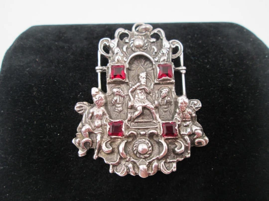 Medalla colgante pórtico. Plata de ley y granates. Escena relieve rey con querubines