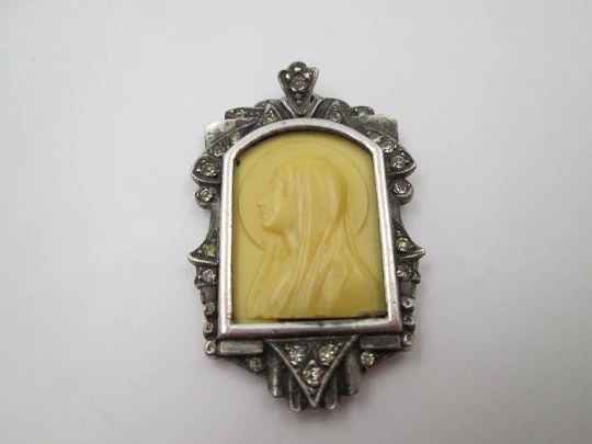 Medalla colgante Virgen. Plata de ley y zafiros blancos. Talla marfil. Cerco vegetal. 1950