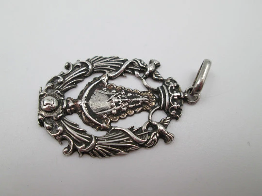 Medalla religiosa calada. Virgen María con manto y bastón de mando. Plata de ley. 1960