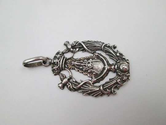 Medalla religiosa calada. Virgen María con manto y bastón de mando. Plata de ley. 1960