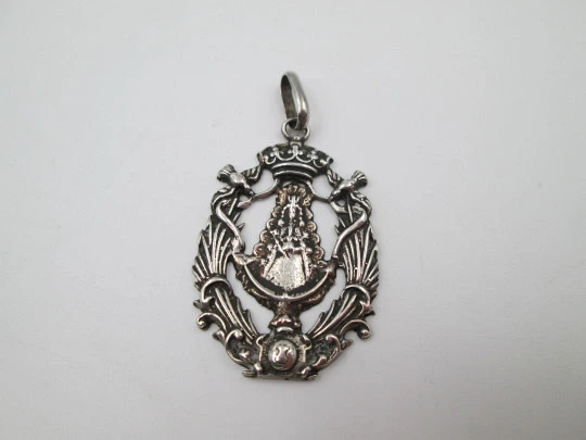 Medalla religiosa calada. Virgen María con manto y bastón de mando. Plata de ley. 1960