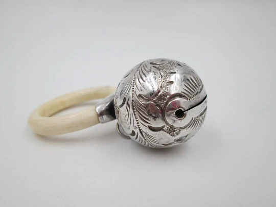 Ornate sphere baby rattle. Sterling silver. Vegetable motifs. White resin ring. 1970's