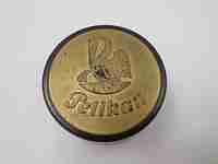 Pelikan round garnet bakelite box with golden front. Screw lid top. Germany. 1950's