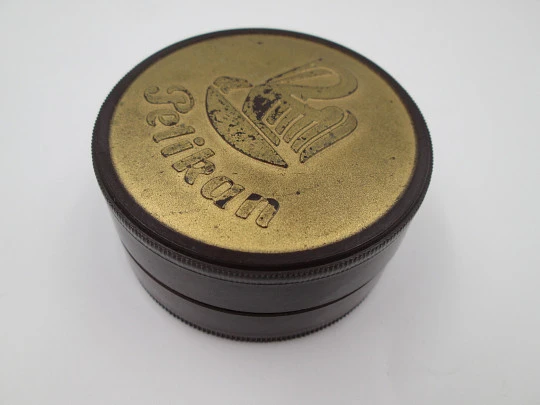 Pelikan round garnet bakelite box with golden front. Screw lid top. Germany. 1950's