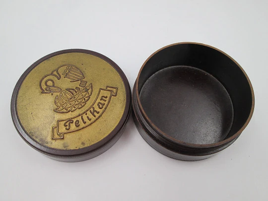 Pelikan round garnet bakelite box with golden front. Screw lid top. Germany. 1950's