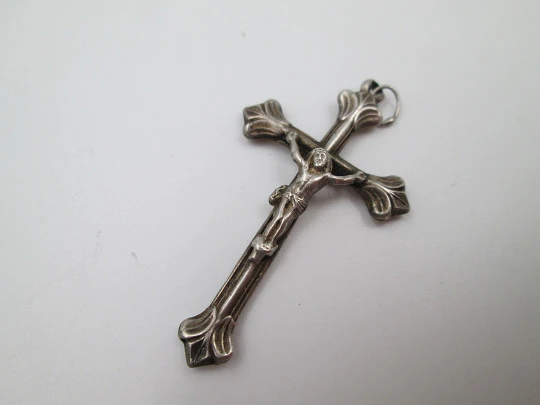 Pequeña cruz crucifijo colgante con remates en flor de lis. Plata de ley. Asa y argolla. 1950