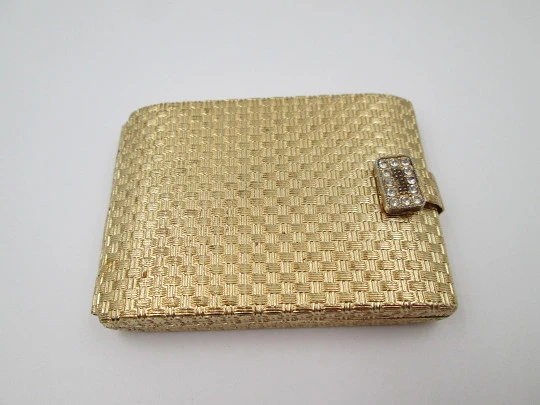 Polvera para mujer. Metal dorado con trama decorativa. Cierre gemas blancas. 1950