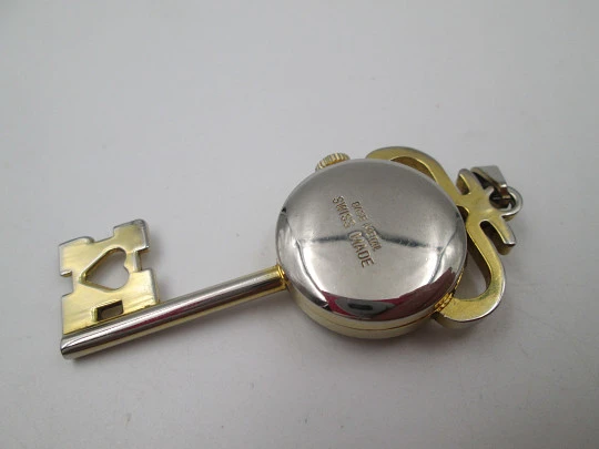 Reloj colgante Jubilora. Metal dorado y acero. Forma de llave. Cuerda manual. Suiza. 1970