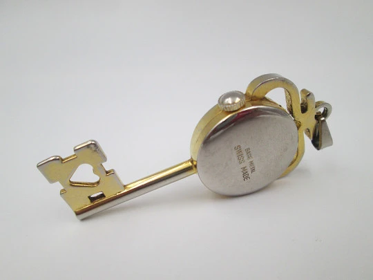 Reloj colgante Jubilora. Metal dorado y acero. Forma de llave. Cuerda manual. Suiza. 1970
