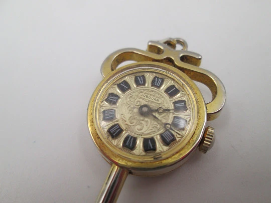 Reloj colgante Jubilora. Metal dorado y acero. Forma de llave. Cuerda manual. Suiza. 1970