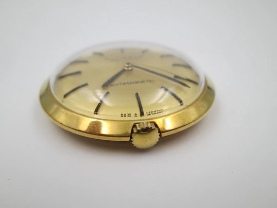 Reloj colgante Kienzle Markant. Metal chapado oro. Cuerda manual. Alemania. 1960