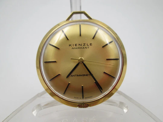 Reloj colgante Kienzle Markant. Metal chapado oro. Cuerda manual. Alemania. 1960