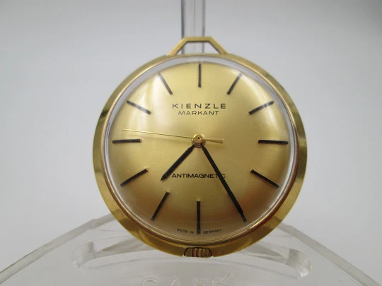 Reloj colgante Kienzle Markant. Metal chapado oro. Cuerda manual. Alemania. 1960