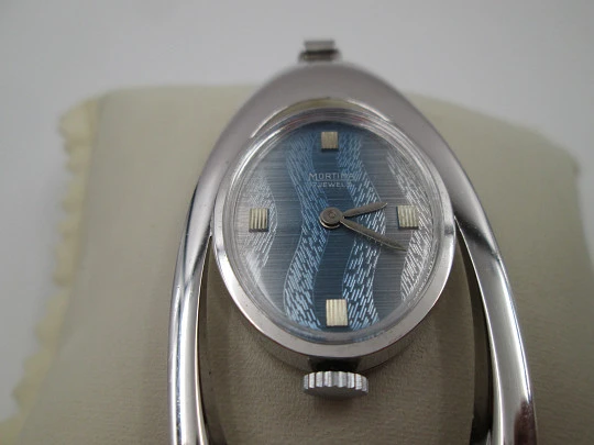 Reloj colgante Mortima. Metal plateado. Esfera bicolor. Forma elíptica. Francia. 1970