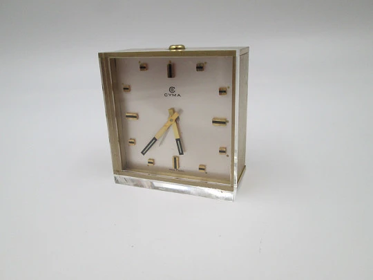 Reloj despertador de sobremesa Cyma. Cuerda manual. Bronce y metacrilato. Suiza. 1960