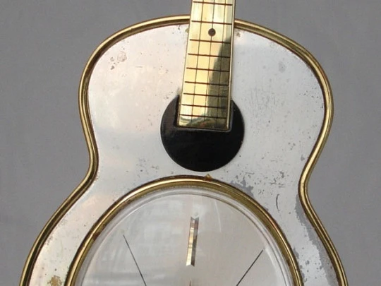 Reloj musical Swiza. Cuerda manual. Bronce. Forma guitarra. 1970