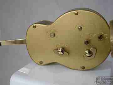 Reloj musical Swiza. Cuerda manual. Bronce. Forma guitarra. 1970