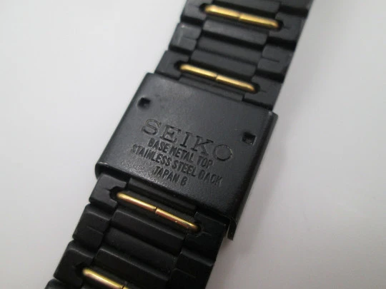 Seiko. Metal negro y oro. Fondo acero. Cuarzo. Caja cuadrada. Brazalete. 1980. Japón