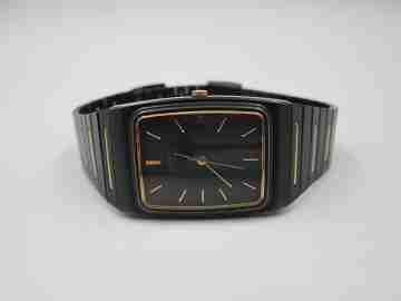 Seiko. Metal negro y oro. Fondo acero. Cuarzo. Caja cuadrada. Brazalete. 1980. Japón