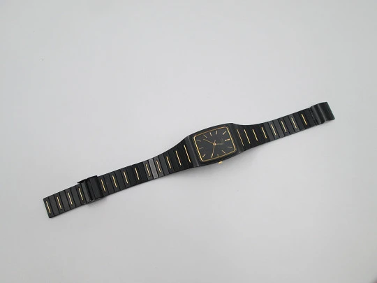 Seiko. Metal negro y oro. Fondo acero. Cuarzo. Caja cuadrada. Brazalete. 1980. Japón