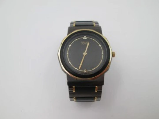 Seiko. Metal negro y oro. Fondo acero. Cuarzo. Caja redonda. Brazalete. 1980. Japón