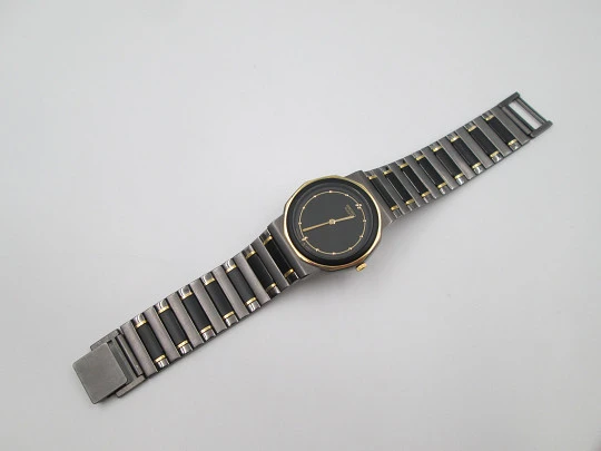 Seiko. Metal negro y oro. Fondo acero. Cuarzo. Caja redonda. Brazalete. 1980. Japón