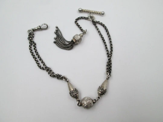 Silver pocket watch chain. Ball and acorns motifs. T-bar. Lobster clasp. Europe. 1910's