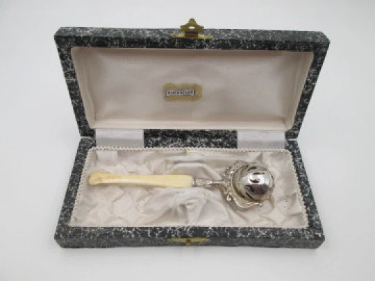 Sonajero. Plata de ley. Esfera calada y mango marfil. 1960. Estuche. Adornos florales