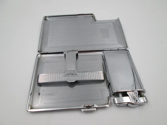 Tiki cigarette case with petrol lighter. Silver plated metal. Waves motifs. England. 1960's