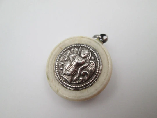 Unisex round pendant. Ivory paste & sterling silver. Warrion and saint relief. 1940's. Europe