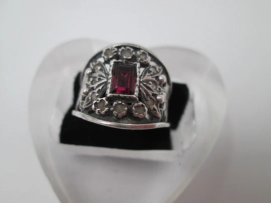 Women's openwork ring. Sterling silver, central garnet and white gems. 1990's