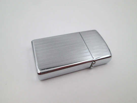 Zippo petrol pocket lighter. Chromed metal. Vertical lines pattern. United States. 1990's